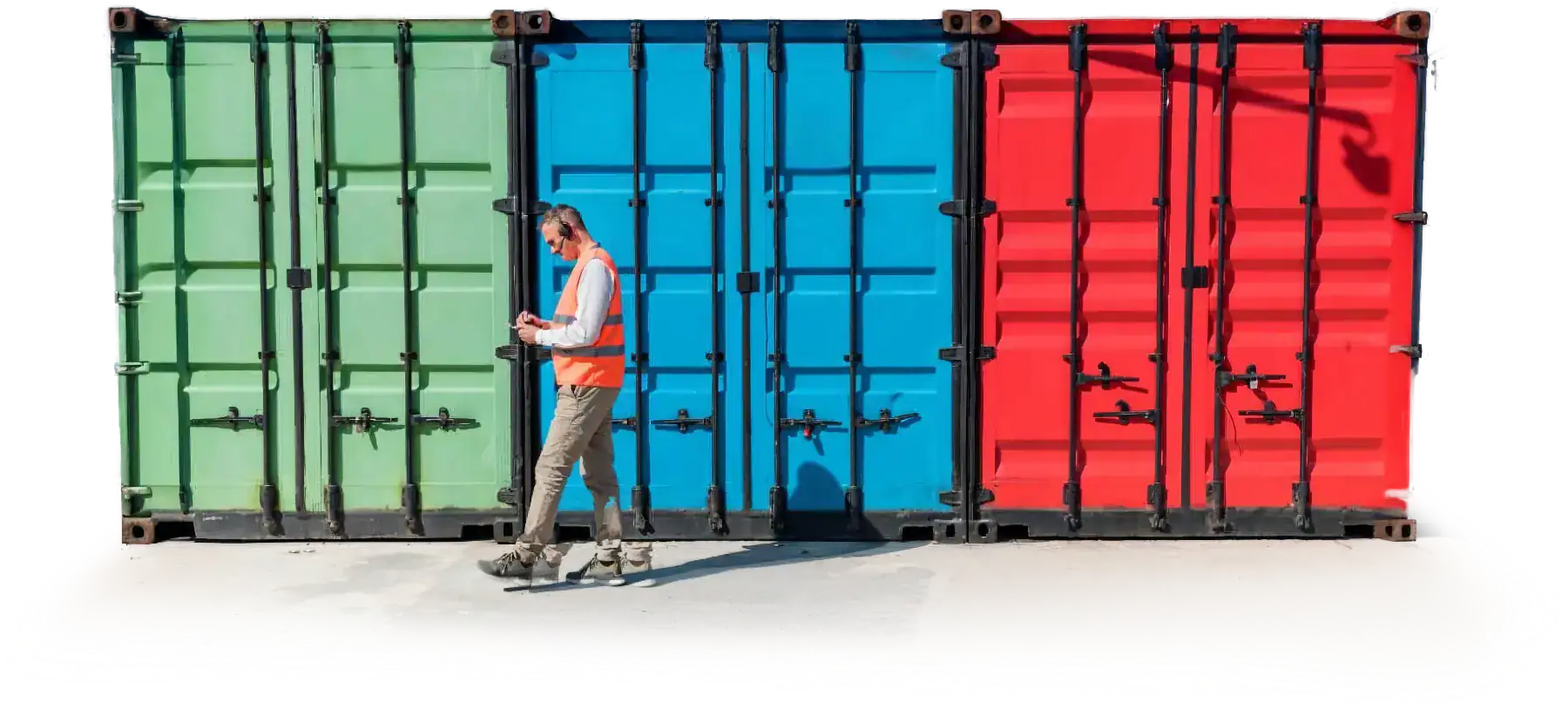 Worker in vest walking by colorful shipping containers.